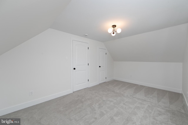 additional living space with light carpet, lofted ceiling, and baseboards