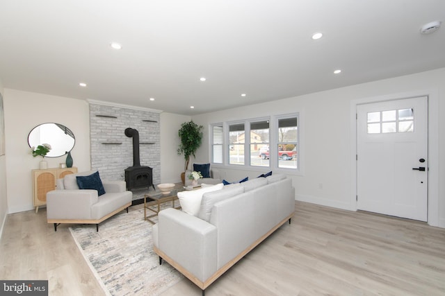 living area with a wood stove, light wood-type flooring, baseboards, and recessed lighting