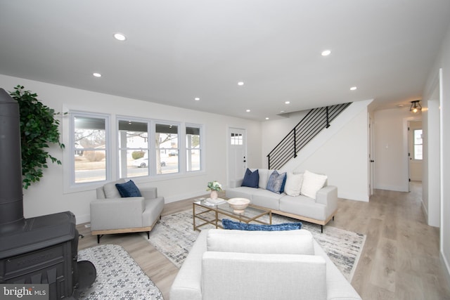 living room featuring a wealth of natural light, light wood-type flooring, recessed lighting, and stairs