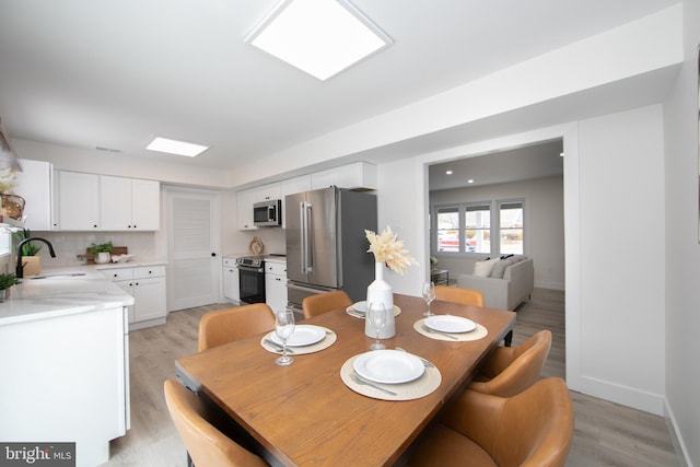 dining area with light wood-type flooring and baseboards