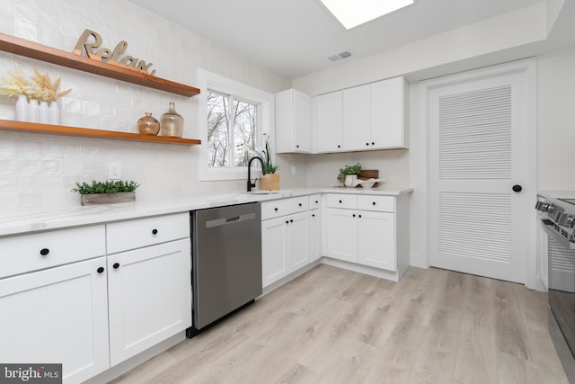 kitchen with visible vents, white cabinetry, light wood finished floors, a sink, and stainless steel dishwasher