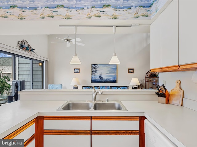 kitchen with dishwasher, light countertops, hanging light fixtures, white cabinetry, and a sink