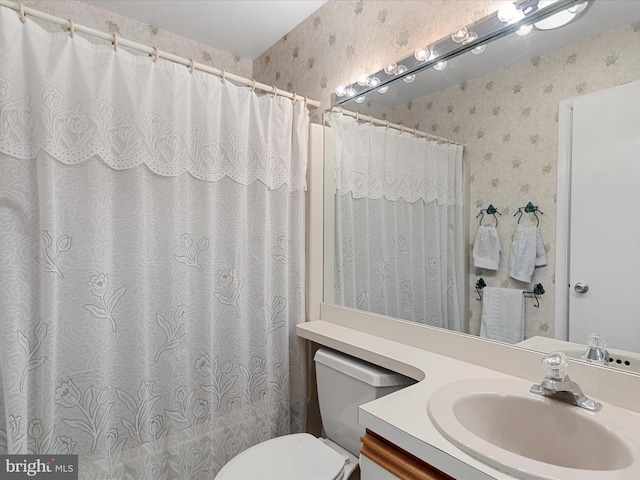 bathroom with a shower with shower curtain, toilet, vanity, and wallpapered walls