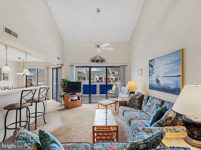 living area with visible vents, light carpet, high vaulted ceiling, and a ceiling fan