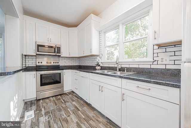 kitchen featuring a sink, light wood-style floors, white cabinets, appliances with stainless steel finishes, and tasteful backsplash