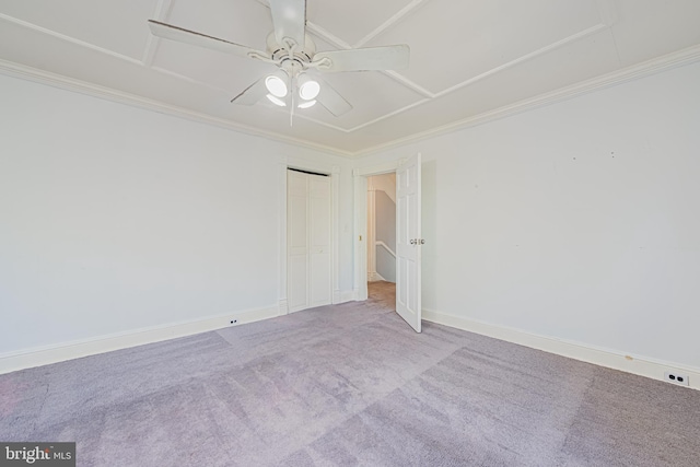 carpeted empty room with a ceiling fan, baseboards, and crown molding