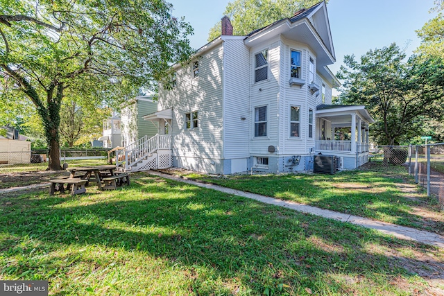 view of side of home with a chimney, fence, and a lawn