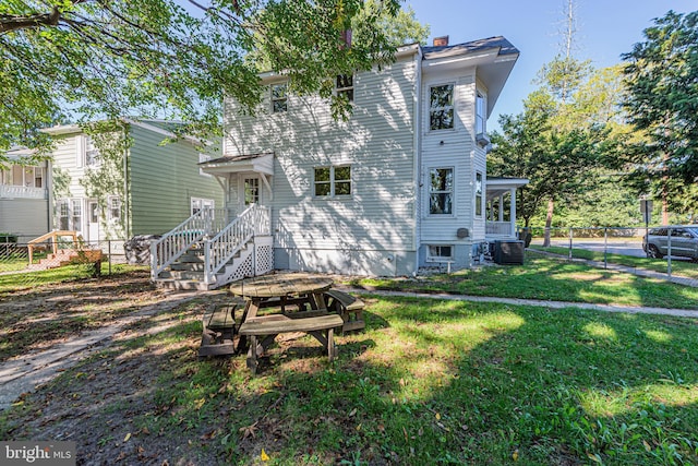 view of front of house featuring a front yard, fence, a chimney, and central AC unit