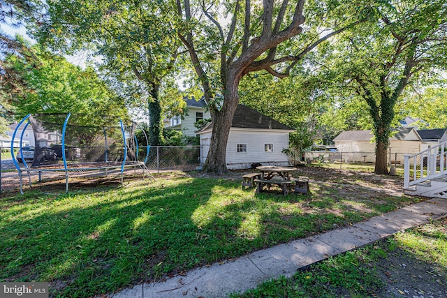 view of yard featuring a fenced backyard, a trampoline, and a fire pit