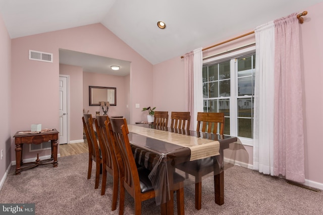 carpeted dining area with baseboards, visible vents, and vaulted ceiling