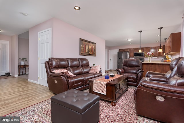 living area featuring baseboards, light wood-style flooring, and recessed lighting