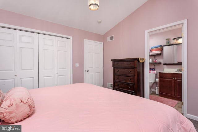 carpeted bedroom featuring lofted ceiling, ensuite bath, visible vents, and a closet