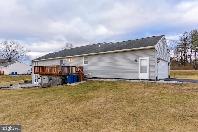 back of house featuring a garage, a lawn, and a wooden deck