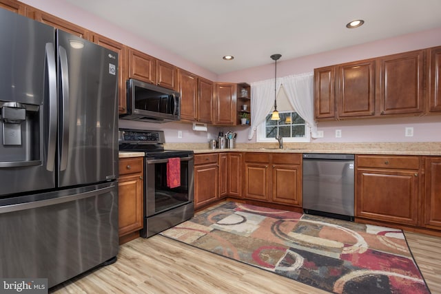 kitchen featuring brown cabinets, light wood finished floors, open shelves, appliances with stainless steel finishes, and a sink