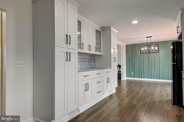 bar featuring tasteful backsplash, dark wood finished floors, freestanding refrigerator, pendant lighting, and a notable chandelier