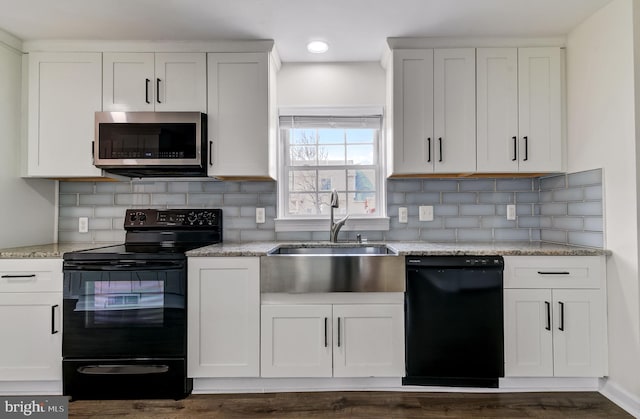 kitchen featuring tasteful backsplash, white cabinets, a sink, light stone countertops, and black appliances