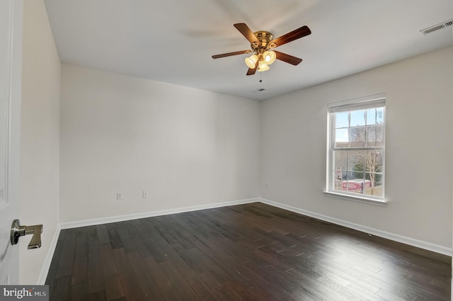 spare room with dark wood-style floors, baseboards, visible vents, and ceiling fan