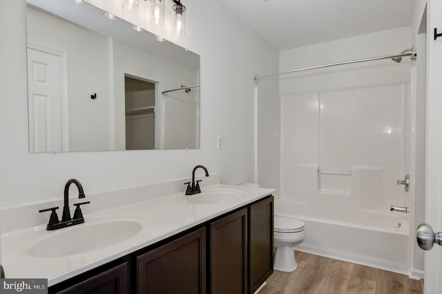 bathroom with double vanity, wood finished floors, a sink, and toilet