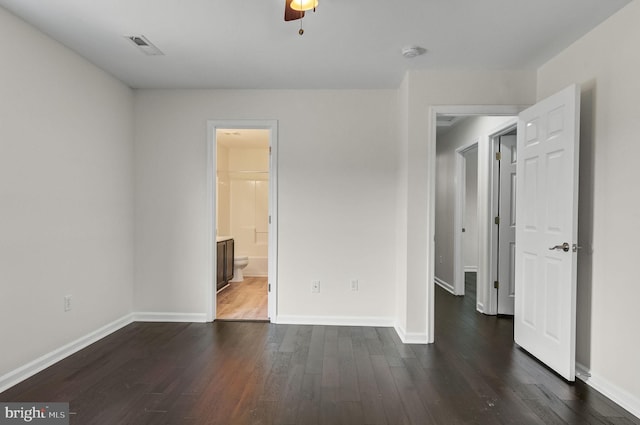 unfurnished bedroom featuring dark wood-style floors, connected bathroom, visible vents, and baseboards