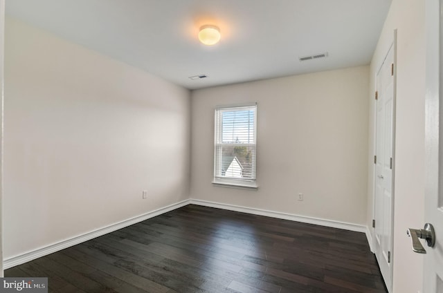 unfurnished bedroom with dark wood-type flooring, visible vents, and baseboards