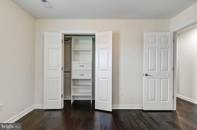 unfurnished bedroom featuring baseboards, a closet, visible vents, and dark wood-type flooring