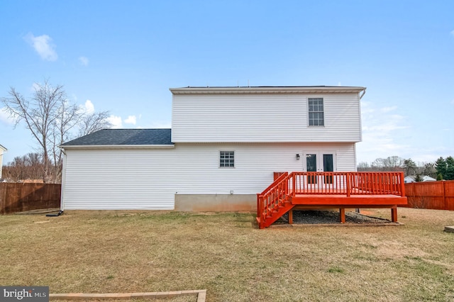 back of property with a fenced backyard, french doors, a lawn, and a wooden deck