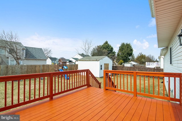 wooden terrace with a residential view, a fenced backyard, a lawn, and an outdoor structure