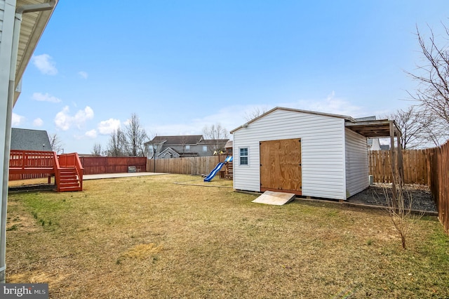 view of yard featuring a fenced backyard, an outdoor structure, a playground, and a storage unit