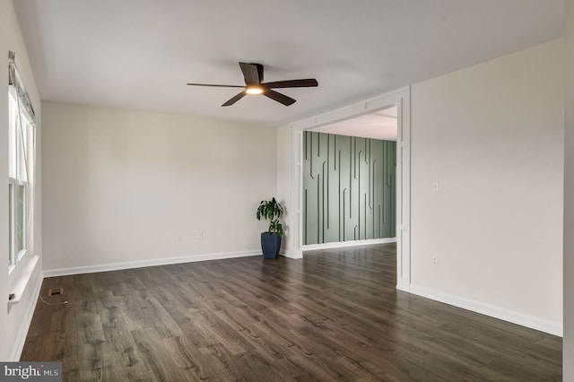 spare room featuring dark wood finished floors, a ceiling fan, and baseboards