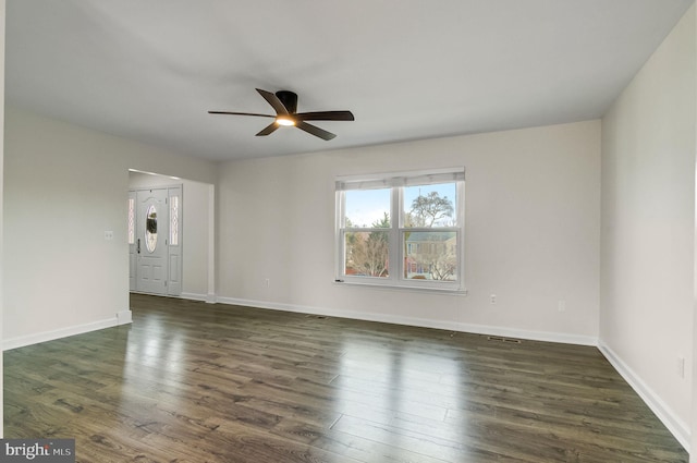 spare room with ceiling fan, dark wood-style flooring, visible vents, and baseboards