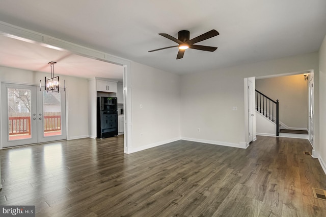 spare room with baseboards, dark wood finished floors, stairs, french doors, and ceiling fan with notable chandelier