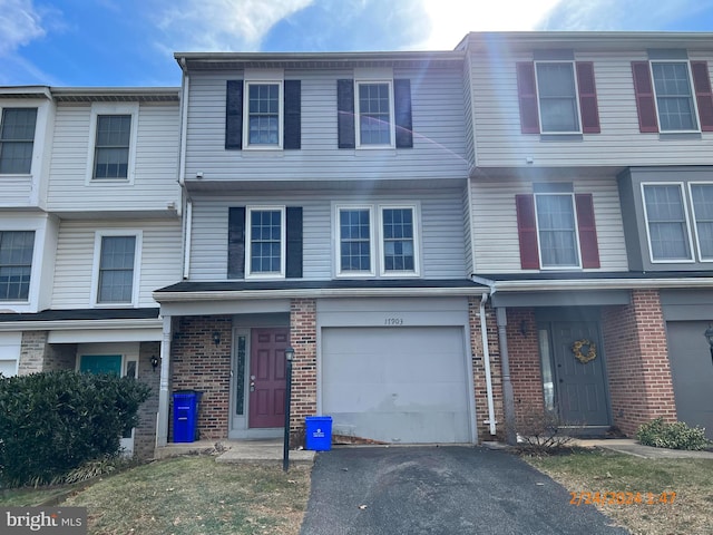 multi unit property featuring an attached garage, driveway, and brick siding