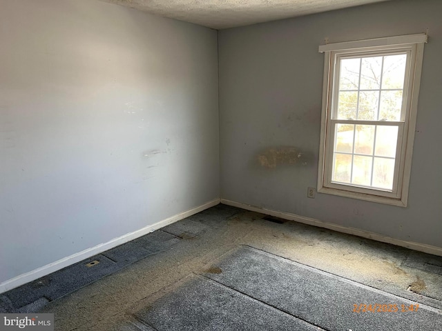 spare room featuring visible vents, baseboards, and a textured ceiling