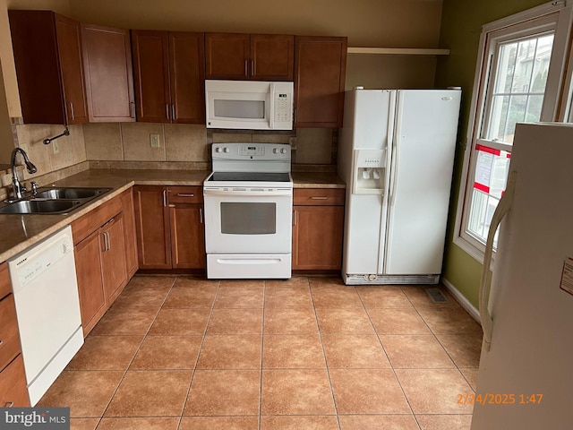 kitchen featuring plenty of natural light, white appliances, light tile patterned flooring, and a sink