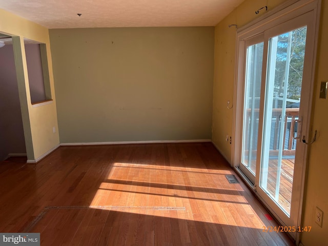 spare room featuring hardwood / wood-style floors, visible vents, and baseboards