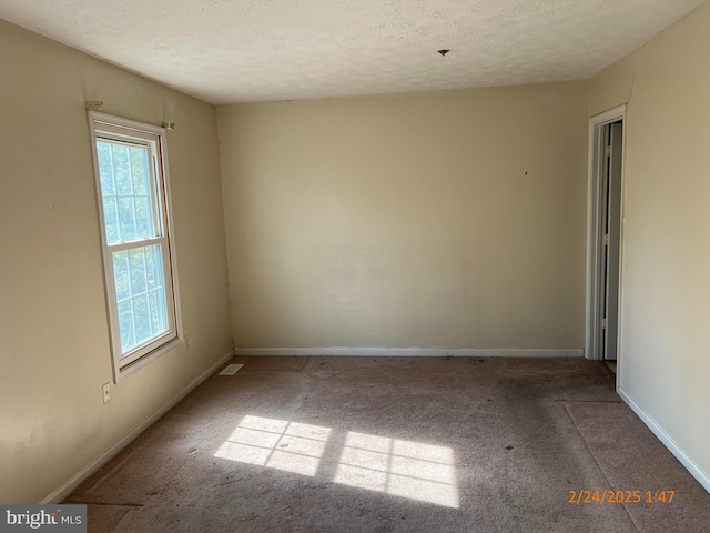 carpeted empty room with visible vents, baseboards, and a textured ceiling