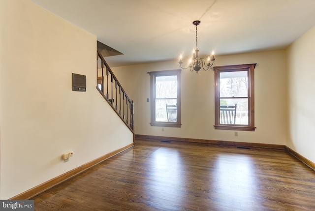 unfurnished room featuring baseboards, visible vents, dark wood finished floors, stairway, and a notable chandelier