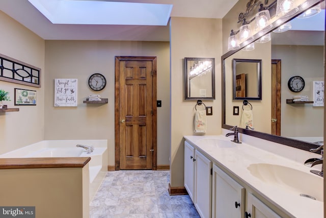 bathroom featuring a skylight, a garden tub, a sink, and double vanity