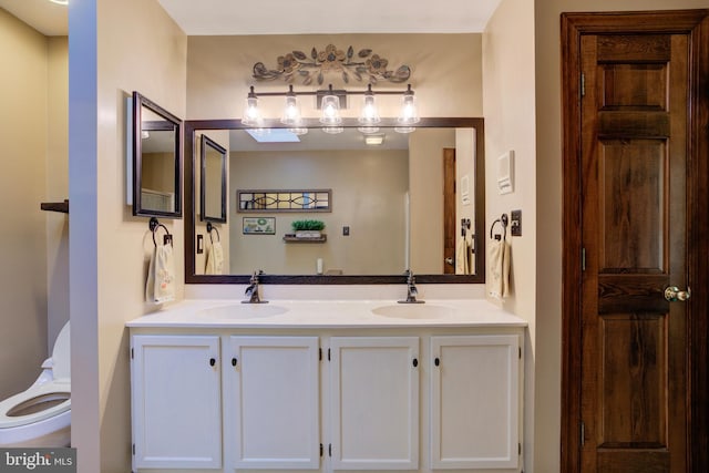 bathroom with double vanity, a sink, and toilet