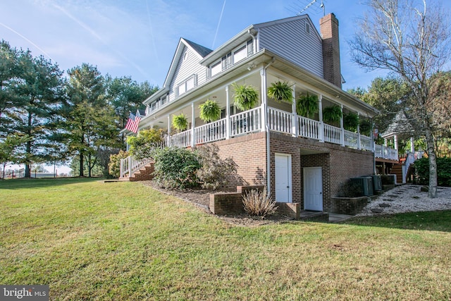 view of home's exterior with brick siding, a yard, a chimney, stairway, and a wooden deck