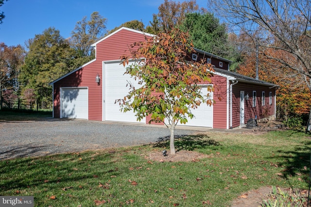 view of side of home featuring a detached garage, a lawn, and an outbuilding