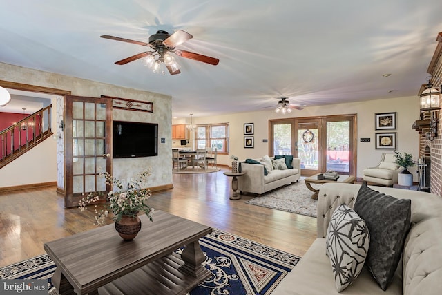 living room featuring stairs, a fireplace, baseboards, and wood finished floors