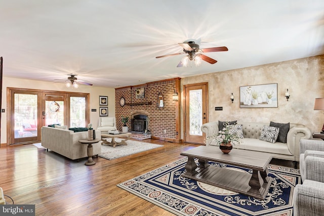 living area with a wood stove, wood finished floors, and a ceiling fan