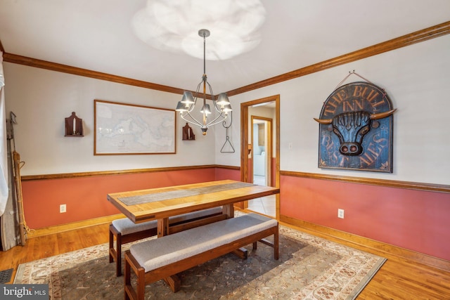 dining space with baseboards, a notable chandelier, ornamental molding, and wood finished floors