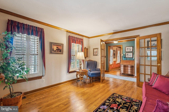 living area with baseboards, ornamental molding, and wood finished floors