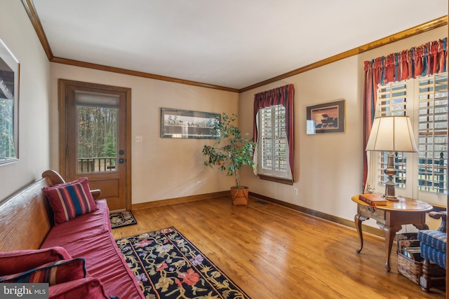 sitting room with ornamental molding, wood finished floors, and baseboards