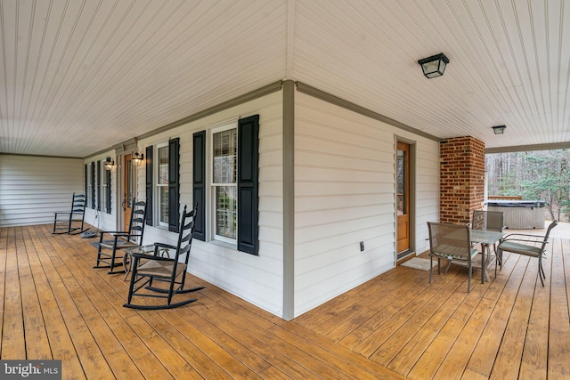 wooden terrace with a hot tub and a porch