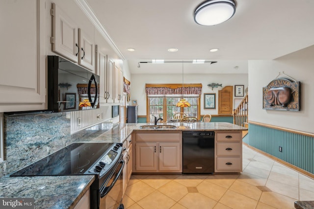 kitchen featuring light tile patterned flooring, a wainscoted wall, a peninsula, a sink, and black appliances