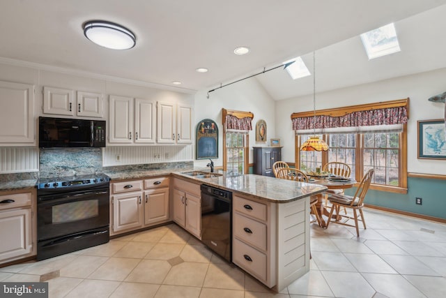 kitchen featuring vaulted ceiling with skylight, a peninsula, a sink, black appliances, and tasteful backsplash