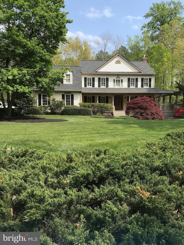 view of front of property featuring a porch, a chimney, a front lawn, and roof with shingles